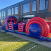 Opblaasbare stormbaan van 17,5 meter in rood-blauwe kleuren, met diverse hindernissen zoals klimdelen, kruiptunnels en obstakels, opgesteld op een witte achtergrond.
