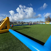 Voetbalboarding 6vs6 – Compleet voetbalveld opblaasbaar (overzicht) Overzicht van de opblaasbare voetbalboarding 6vs6 op een sportveld, met kinderen langs de zijlijn en een gele goal aan de andere kant.