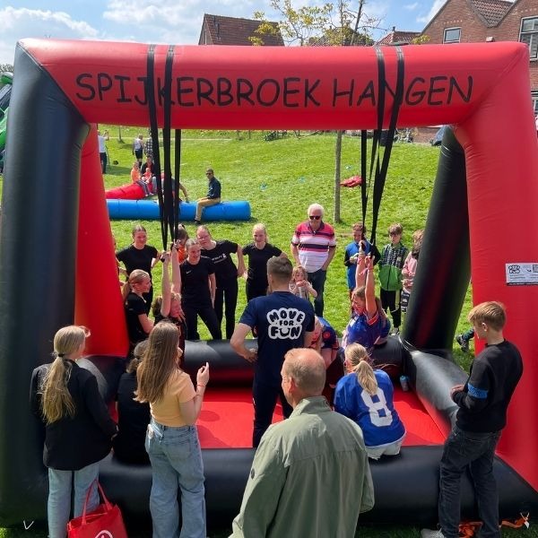 Opblaasbaar spijkerbroek hangen spel in rood en zwart met twee deelnemers die aan de broeken hangen.