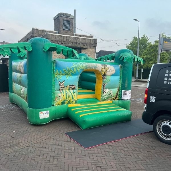 Groen jungle springkussen met palmbomen en dierenillustraties, ideaal voor verhuur op kinderfeestjes en thema-evenementen.