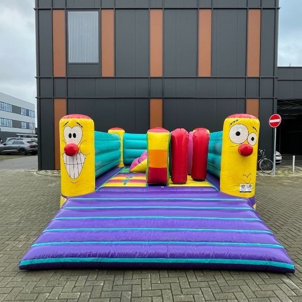 Springkussen Playbounce – vrolijk speelspringkussen met obstakels Kleurrijk Playbounce springkussen met lachende figuren en zachte obstakels, perfect voor verhuur op kinderfeestjes en speeldagen.