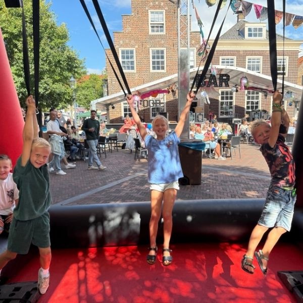 Opblaasbaar spijkerbroek hangen spel in rood en zwart met twee deelnemers die aan de broeken hangen.