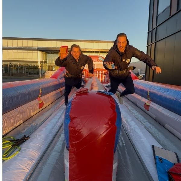 Overzicht van de opblaasbare Bungee Run Sterkste Man met twee banen en verkeerspionnen.