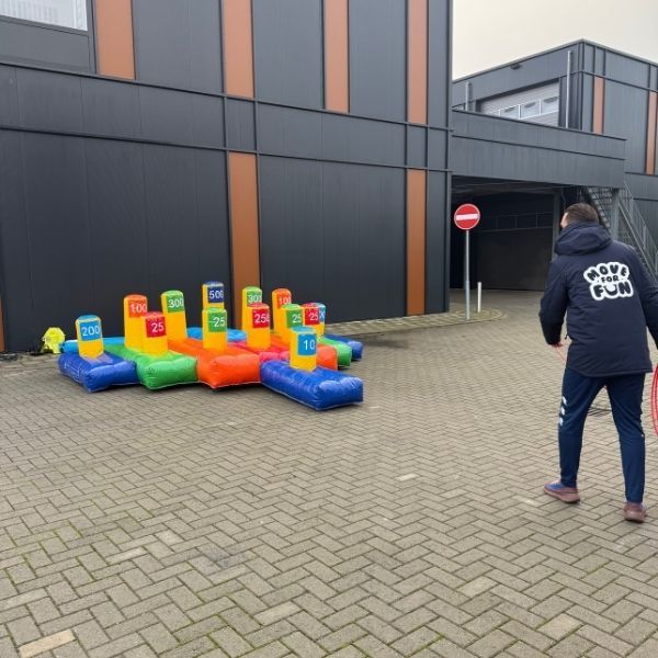 Ringgooien opblaasbaar Opblaasbaar ringgooien spel met gekleurde puntenblokken en ringen, opgesteld op straat.